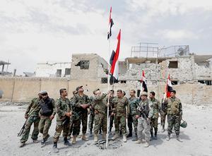 Syrische soldaten hijsen de vlag in een wijk van Damascus die terugveroverd is op de IS. beeld EPA