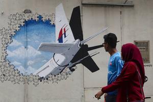 Voorbijgangers passeren in Kuala Lumpur een muurschildering van de vermiste Boeing 777 van Malaysia Airlines. Vlucht MH370 is vandaag vijf jaar van de radar verdwenen.  beeld EPA, Fazry Ismail