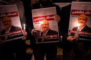 Betogers houden posters met de afbeelding van Khashoggi omhoog bij het consulaat van Saoedi-Arabië in Istanbul. beeld AFP