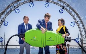 Koning Willem-Alexander opent het windpark bij de Krammersluizen door symbolisch een stekker in het stopcontact te steken. Naast hem de directeur van Zeeuwind, Teus Baars (l.), en van Deltawind, Monique Sweep (r.). beeld ANP, Frank van Beek