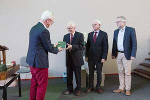 Nico de Waal (KokBoekencentrum) overhandigt het eerste deel van Van Rulers werk over de kerk aan de redactie (van links naar rechts) dr. P. van den Heuvel, drs. J. Stelwagen en dr. D. van Keulen.  beeld RD, Anton Dommerholt