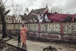 Een vrouw met haar kind staat bij beschadigde gebouwen in Beira, Mozambique, afgelopen zondag. Het grootste deel van Beira ligt in puin, nadat een verwoestende orkaan door de stad raasde. beeld Internation Federation of Red Cross and Red Crescent Societies (IFRC)