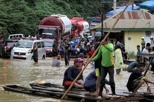 Gestrand verkeer bij een weg die onder water staat in Andadowi, in de Indonesische provincie Zuidoost-Sulawesi. Door grote overstromingen moesten alleen in deze provincie al ruim 4.000 mensen evacuëren. beeld AFP, Suwarjono