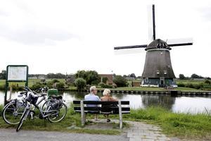 Fietsers rusten langs de Ringvaart van De Beemster. Fietsen en molens worden door veel Nederlanders gezien als typerend voor de Nederlandse identiteit. beeld ANP, Koen Suyk