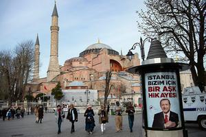 Mensen lopen langs een verkiezingsposter van de Turkse president Erdogan, afgelopen dinsdag. Op de achtergrond de Hagia Sophia, Istanbul. beeld AFP