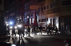 Mensen steken een straat over tijdens een stroomstoring in Caracas op 7 maart 2019. beeld AFP