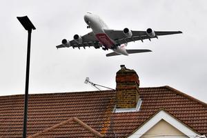 Een vliegtuig vliegt over huizen in de buurt van Heathrow Airport. beeld AFP