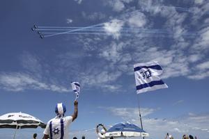 Israëliërs kijken donderdag op het strand van Tel Aviv naar een luchtshow van de Israëlische luchtmacht ter gelegenheid van de 71e Onafhankelijkheidsdag. Israël herdacht donderdag de het uitroepen van de moderne Joodse staat in 1948 door David Ben Goerion. In het hele land waren festiviteiten ter gelegenheid van de nationale feestdag. Onafhankelijkheidsdag werd in de synagogen ingeluid met een speciaal gebed. beeld EPA, Abir Sultan