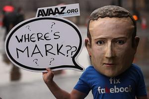 Een betoger met een masker van Facebook-topman Mark Zuckerberg staat bij Portcullis House, waar het Britse parlement samenkomt. De man toont daarmee zijn ongenoegen over het feit dat Zuckerberg niet is komen opdagen voor de hoorzitting over fake news in Londen. Op die zitting waren politieke vertegenwoordigers van negen landen aanwezig. Ze stelden kritische vragen over nepnieuws en desinformatie via het sociale netwerk Facebook. beeld AFP