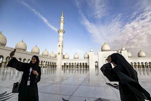 Vrouwen maken een selfie op het plein voor de Sjeik Zayed Grote Moskee in Abu Dhabi, net voor het bezoek van paus Franciscus aan de Verenigde Arabische Emiraten begin vorige maand. beeld AFP, Vincenzo Pinto