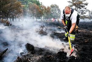 Brandweerlieden blussen na bij de natuurbrand bij het Drentse Wateren. Na een grote heidebrand werd in augstus 2018 zo'n 75 hectare heide zwartgeblakerd. beeld ANP