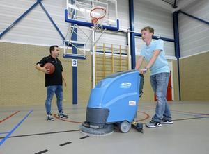 William Kramer (r.), die en beperking heeft, doet in sporthal De Vlechttuinen in Urk onder meer schoonmaakwerk. Links zijn begeleider Frans Kramer.   beeld Ruud Ploeg