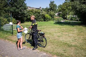 Een buurtbewoner spreekt met een wijkagent bij het speeltuintje in Assen. beeld ANP