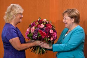 De Duitse bondskanselier Angela Merkel was vorige week woensdag jarig en kreeg daarom tijdens de ministerraad bloemen van minister van Justitie Christine Lambrecht. beeld AFP, John MacDougall