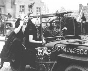 Twee Zeeuwse vrouwen rijden mee op een jeep van de geallieerden tijdens de bevrijding van Nederland.  beeld ANP
