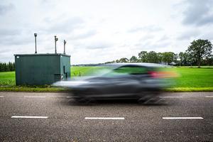 Een auto rijdt langs een meetstation van de RIVM. beeld ANP