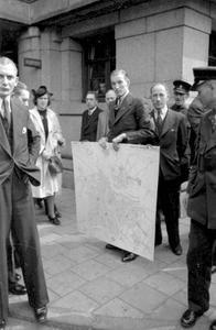 Voor het stadhuis op de Oudezijds Voorburgwal biedt een ambtenaar een plattegrond van Amsterdam aan de Duitse commandant Major Brückner, 15 mei 1940.  beeld Beeldbank WO2 – NIOD – Stapf Bilderdienst.