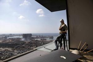 Een gewonde inwoner van Beiroet kijkt vanuit zijn appartement naar de verwoestingen die de explosie van dinsdag in de Libanese hoofdstad heeft aangericht.  beeld AFP, Patrick Baz