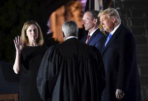 In het bijzijn van haar echtgenoot legde Amy Coney Barrett (l.) maandag in Washington ten overstaan van opperrechter Clarence Thomas en president Donald Trump de eed af die haar benoeming tot rechter van het Amerikaanse hooggerechtshof bezegelde. beeld AFP, Nicholas Kamm