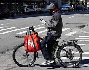 Een bezorger van Grubhub kijkt in New York op zijn telefoon. Het Nederlands-Britse maaltijdbestelbedrijf Just Eat Takeaway neemt zijn Amerikaanse branchegenoot Grubhub over. beeld AFP, Cindy Ord