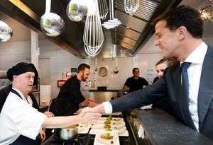 Premier Mark Rutte groet een werknemer van een restaurant in Almelo dat wordt gerund door mensen met een licht verstandelijke beperking. beeld ANP, Piroschka van de Wouw