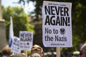 "Nooit weer" staat te lezen op een bord dat een betoger omhoog houdt tijdens een demonstratie in Londen op 4 juli waar antisemitistische slogans werden geroepen. beeld AFP, Jack Taylor