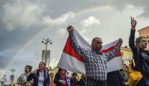 Een man houdt een historische wit-rood-witte vlag van Wit-Rusland vast tijdens protesten van de oppositie. beeld AFP, Sergei Gapon
