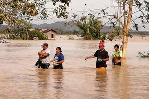 Inwoners van Ormoc waden door het water na overstromingen als gevolg van de tyfoon Phanfone. beeld AFP