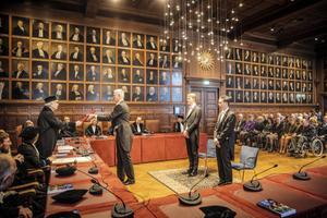 Ds. W. J. Dekker ontvangt de doctorsbul, vergezeld van zijn zoons Arnold en Wim. beeld RD, Henk Visscher