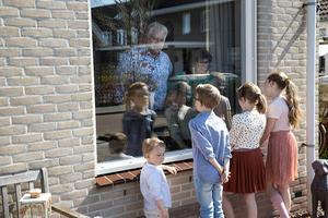 Opa en oma Knulst uit Oosterwolde krijgen raamvisite van hun kleinkinderen Samuël (2), Lourens (9), Hadassa (10) en Thamar (12, rechts). beeld RD, Anton Dommerholt