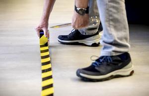 Een werknemer brengt tape op de werkvloer aan om te zorgen dat consumenten 1,5 meter afstand van elkaar houden. De 1,5 metereconomie zal het beeld in winkelstraten blijvend doen veranderen.  beeld ANP, Sem van der Wal