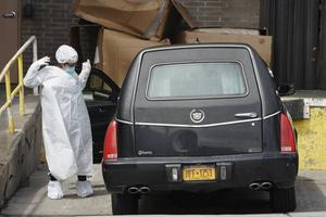 Een begrafenisondernemer in New York trekt beschermende kleding aan. beeld AFP, Bryan R. Smith