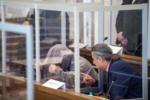Eyad al-Gharib verbergt zich onder zijn capuchon, voorafgaand aan het begin van een rechtsproces tegen hem en een andere aangeklaagde. Ze zouden tientallen mensen hebben vermoord en duizenden gefolterd, toen ze onderdeel uitmaakten van het Assad-regime in Syrië. beeld AFP
