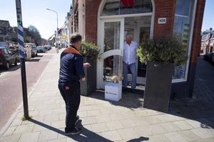 Een postbezorger doet een contactloze bezorging in Haarlem. Bij PostNL is het deze dagen aanzienlijk drukker dan voor de coronacrisis. beeld ANP, Olaf Kraak