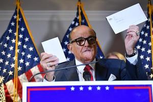 Rudy Giuliani, Trumps persoonlijke advocaat, houdt een envelop van een stembiljet in zijn handen tijdens een persconferentie. beeld AFP, Mandel Ngan