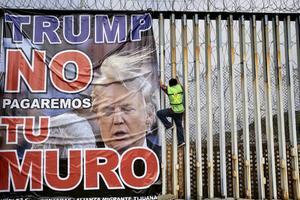 ”Trump, wij betalen niet voor jouw muur”, luidt de tekst op een spandoek dat Mexicanen begin dit jaar bevestigden aan een grenshek dat Mexico van de Verenigde Staten scheidt. beeld AFP, Guillermo Arias