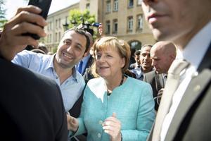 Een asielzoeker maakt een selfie met de Duitse bondskanselier Merkel. In de zomer van 2015 kwamen 800.000 vluchtelingen naar Duitsland, nadat Merkel de grenzen had geopend.  beeld AFP, Bernd von Jutrczenka​