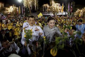 Toeschouwers juichen het Thaise koningspaar toe bij het koninklijk paleis in Bangkok. Als reactie op de protesten blijft de koning langer dan gepland in eigen land. Normaal gesproken woont hij in Duitsland. beeld EPA, Rungroj Yongrit
