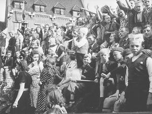 Kinderen en volwassenen juichen en zwaaien naar de geallieerden tijdens de intocht van de bevrijding van Nederland. beeld ANP