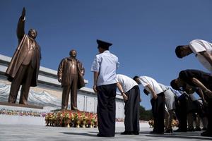 Mensen betuigen hun respect voor bronzen beelden van wijlen leiders Kim Il Sung (l.) en Kim Jong Il. Noord-Koreaanse leiders worden als goden vereerd. Het christendom is verboden in het land. beeld AFP, Andrew Harnik
