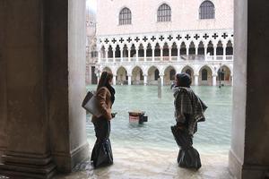 Twee vrouwen bij het overstroomde San Marcoplein in Venetië. beeld EPA