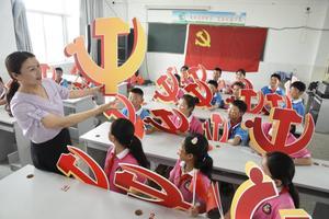 De Chinese overheid doet er alles aan om westerse invloeden door buitenlandse leerkrachten tegen te gaan. Foto: een klas poseert met het embleem van de Communistische Partij. beeld STR/AFP