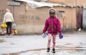 Veel kinderen zijn afhankelijk van school om te kunnen voorzien in hun levensbehoeften met voedselprogramma’s die vanuit scholen worden gecoördineerd. Foto: een kind in Zuid-Afrika op weg naar een voedseluitdeelpunt. beeld ​EPA, Nic Bothma