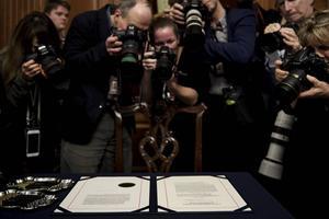 Fotografen verdringen zich rond de papieren waarop de officiële aanklachten tegen president Donald Trump zijn geformuleerd. beeld AFP, Bredan Smialowski