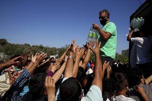 Terwijl in hoofdsteden in Europa wordt gesproken over het opnemen van migranten, strekken vluchtelingen op Lesbos hun handen uit naar water en voedsel. De Nederlandse regering besloot donderdag om honderd migranten op te nemen, ten koste van honderd uit andere landen. Onder leden van de regeringspartijen stuit deze deal echter op weerstand. beeld EPA, Orestis Panagiotou