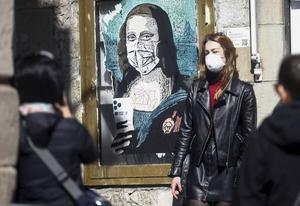 In Barcelona is de Mona Lisa zonder mysterieuze glimlach, maar met telefoon in haar hand te bewonderen. Kunstenaar Salvatore Benintende maakt de muurschildering met de titel ”Mobile World Virus” een week nadat het World Mobile Congres in de Catalaanse stad werd geannuleerd vanwege de coronacrisis. beeld EPA, Quique Garcia