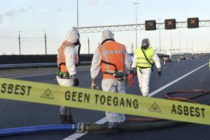 Specialisten ruimen op de A4 bij Hoogmade een zak asbesthoudend puin op. beeld ANP, MediaTV