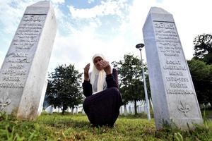 Mejra Djogaz treurt tussen de graven van haar twee zonen Omer en Munib. Ze stierven 25 jaar geleden in Srebrenica.  beeld AFP, Elvis Barukcic