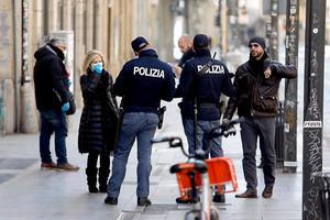 Italiaanse politieagenten controleren in Milaan of burgers een geldige reden hebben om de straat op te gaan. Politie en soldaten worden in het hele land ingezet om ervoor te zorgen dat burgers thuisblijven in een poging verdere verspreiding van het coronavirus te vertragen. beeld EPA, Mourad Balti Touati
