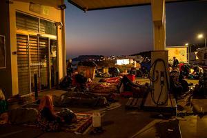 Asielzoekers slapen bij een tankstation bij Mitylini, de hoofdstad van Lesbos. beeld AFP, Angelos Tzortzinis